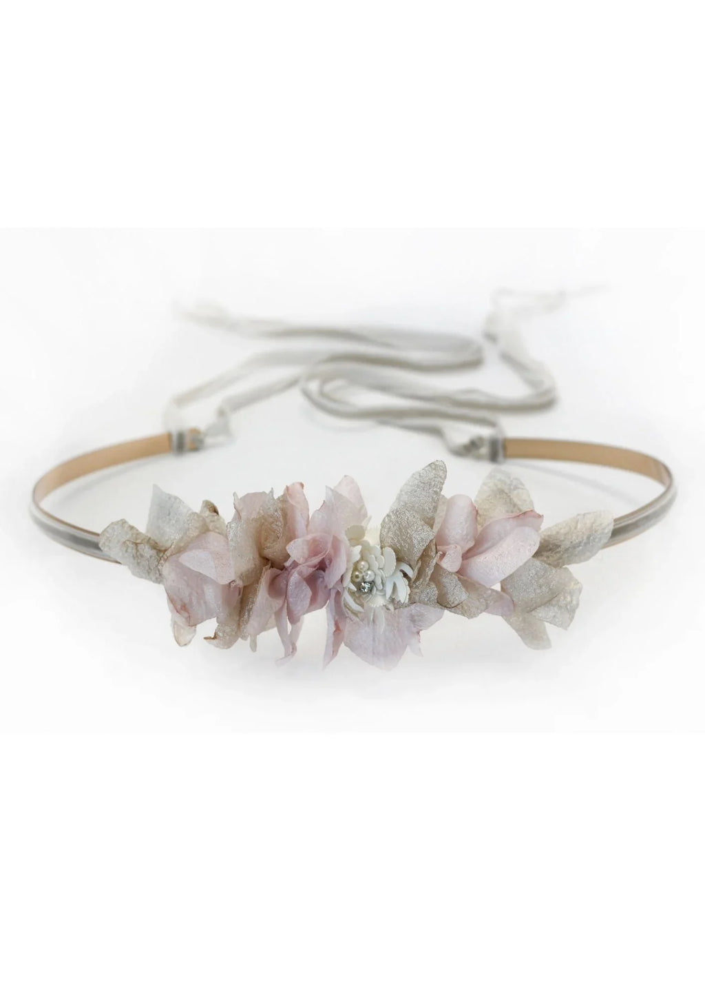 The CINTURÓN IBY is a delicate headband with soft pink and light beige artificial flowers and leaves, finished with thin ties at the back, from nuestra colección diseñada en España, shown on a white background.