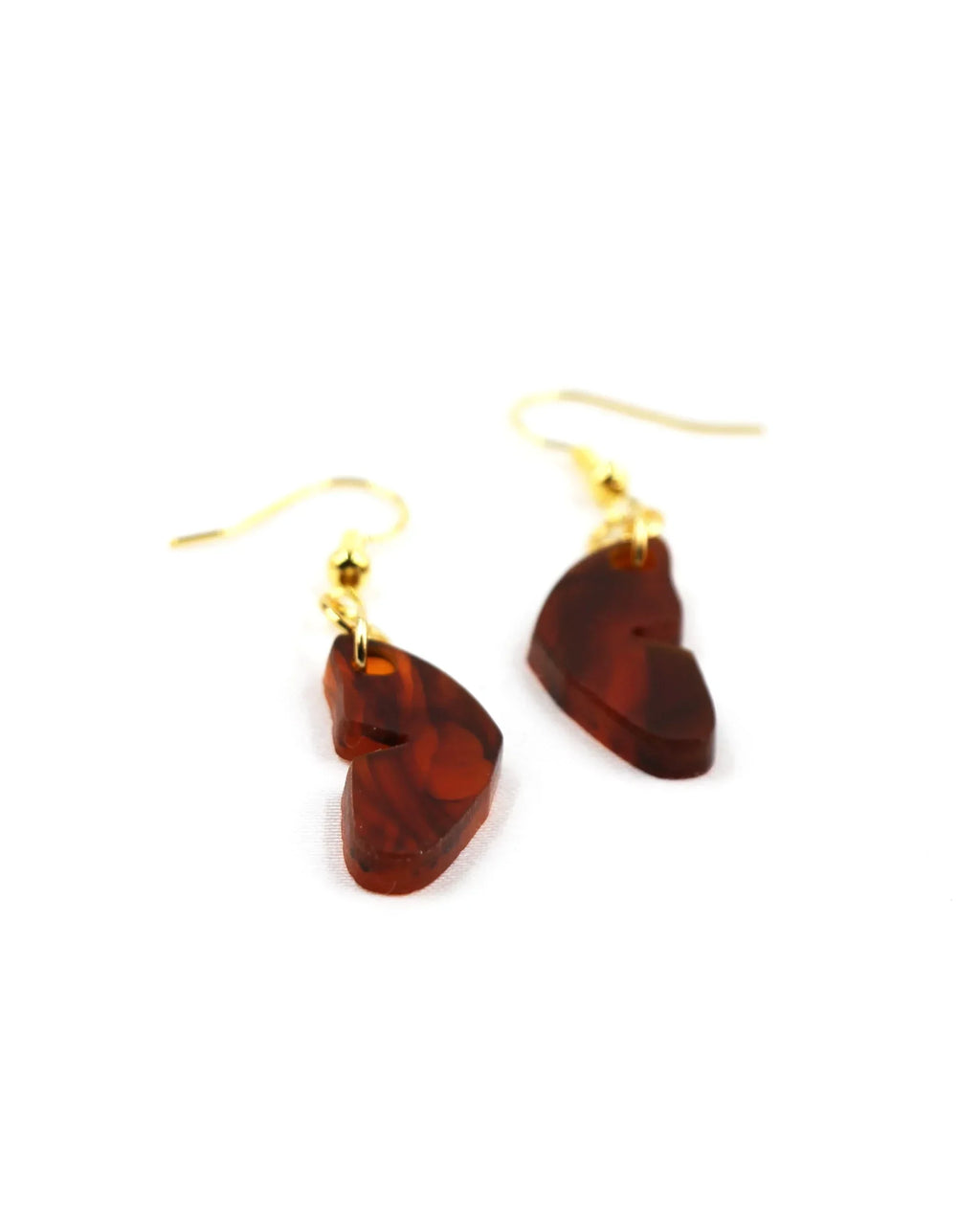Pendientes mariposa: A pair of gold hook earrings with irregular, translucent brown resin charms—un toque de glamour y un colgante único. Displayed on a white background.