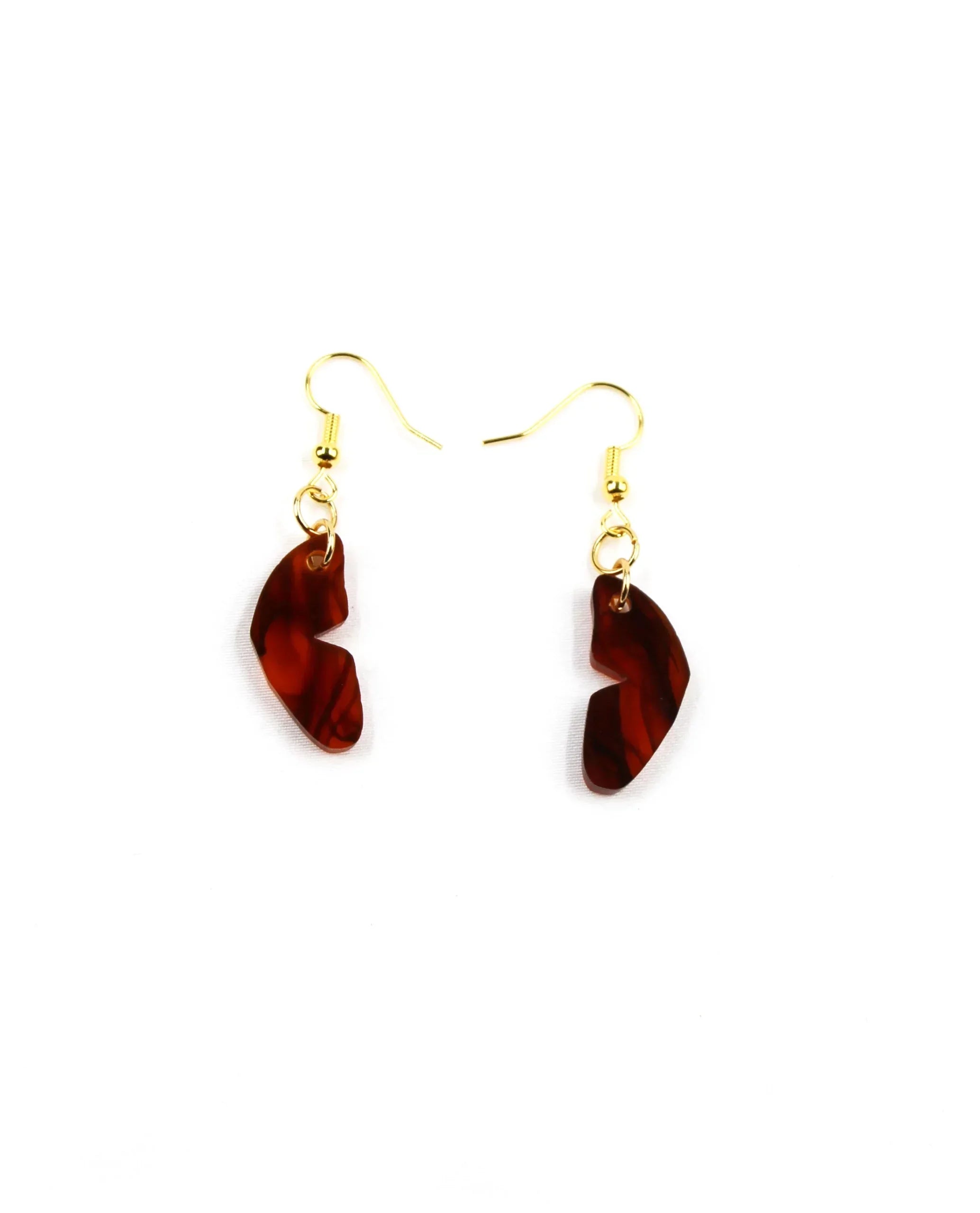 Pendientes mariposa: Gold hook earrings featuring uniquely shaped, translucent dark red charms add a touch of glamour against a white background.